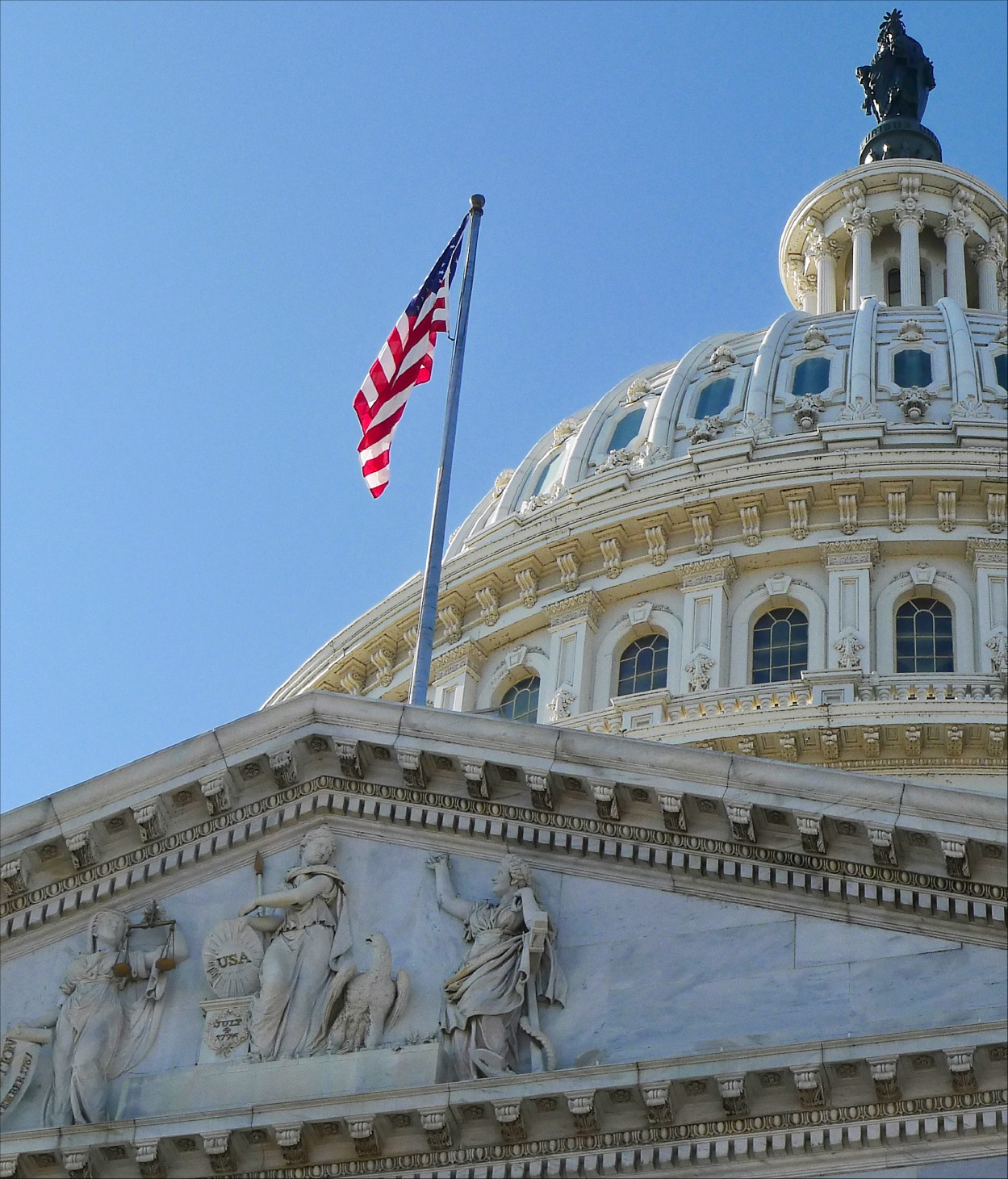 Photo of the US flag on the Capitol's roof in front of the rotunda.