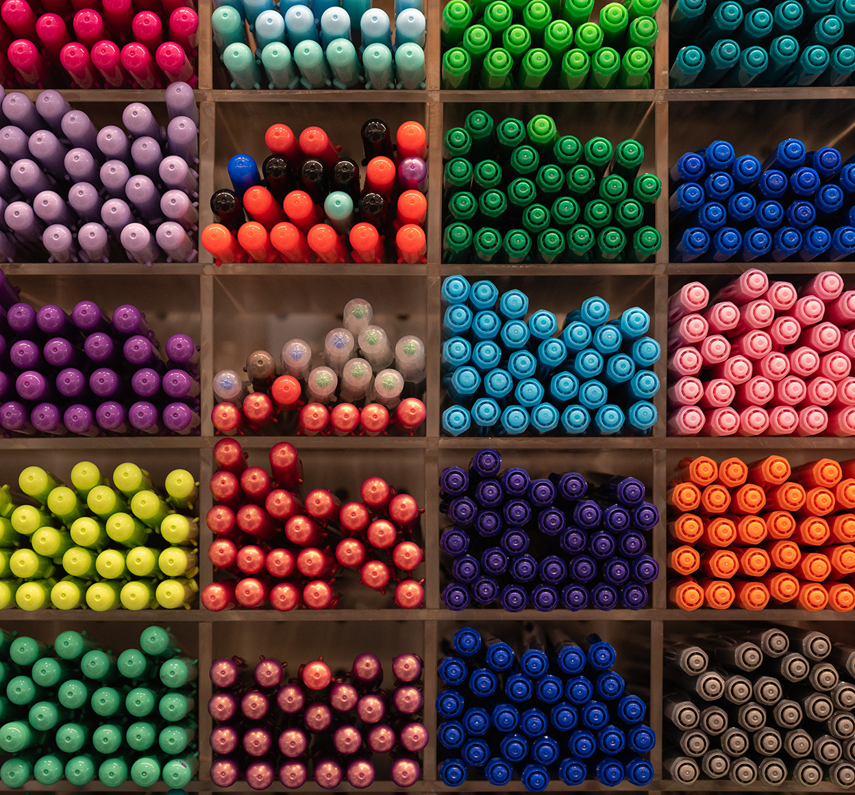 Stylos regroupés par couleur sur des étagères de présentation