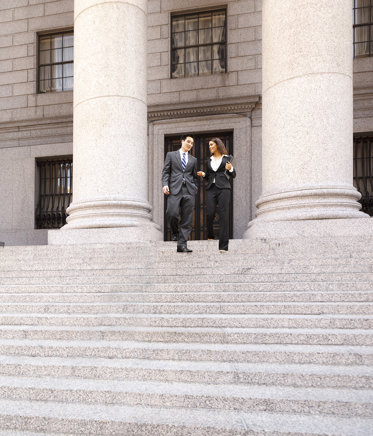 Un avvocato e il suo cliente scendono le scale di pietra anteriori di un tribunale.