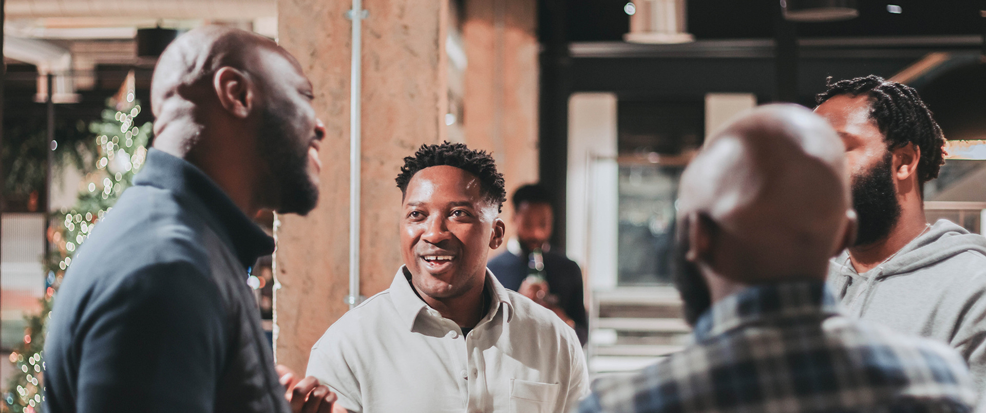 OT-PHOTO-MEN-SPEAKING-IN-A-GROUP Black team members speaking with each other in an office.