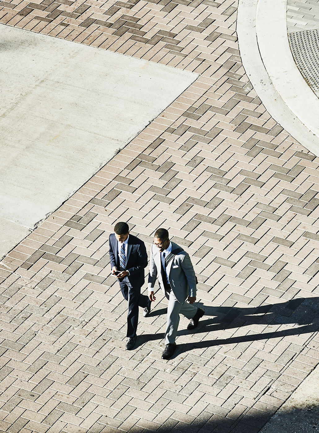 Vista aérea de dos hombres de negocios conversando mientras caminan por una calle céntrica.