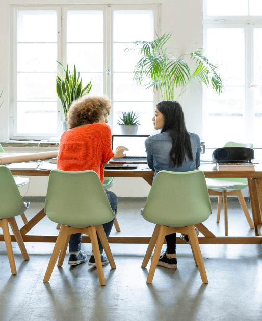 Two women in green chairs having a work discussion