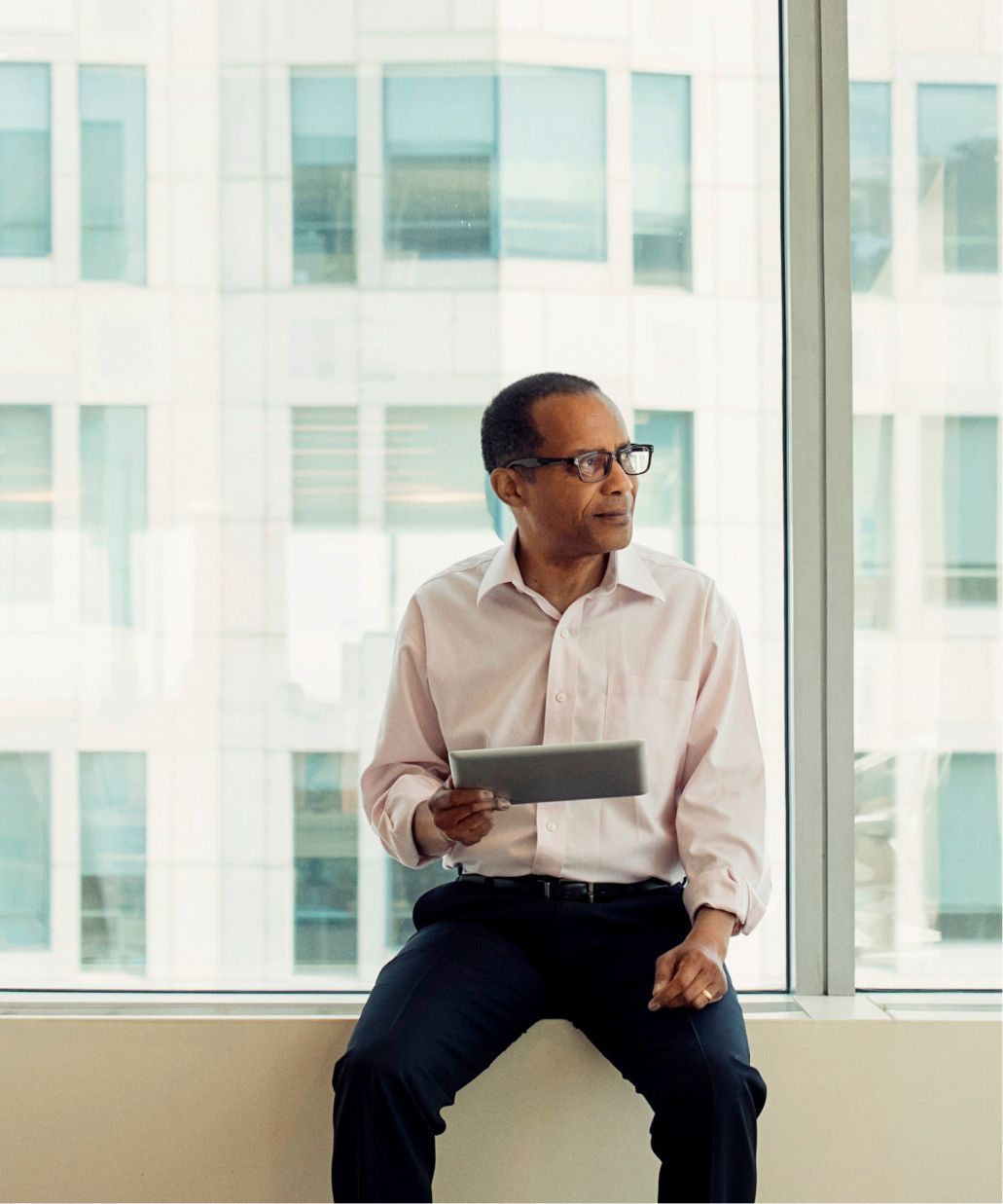 Male office worker with a tablet sitting at a window