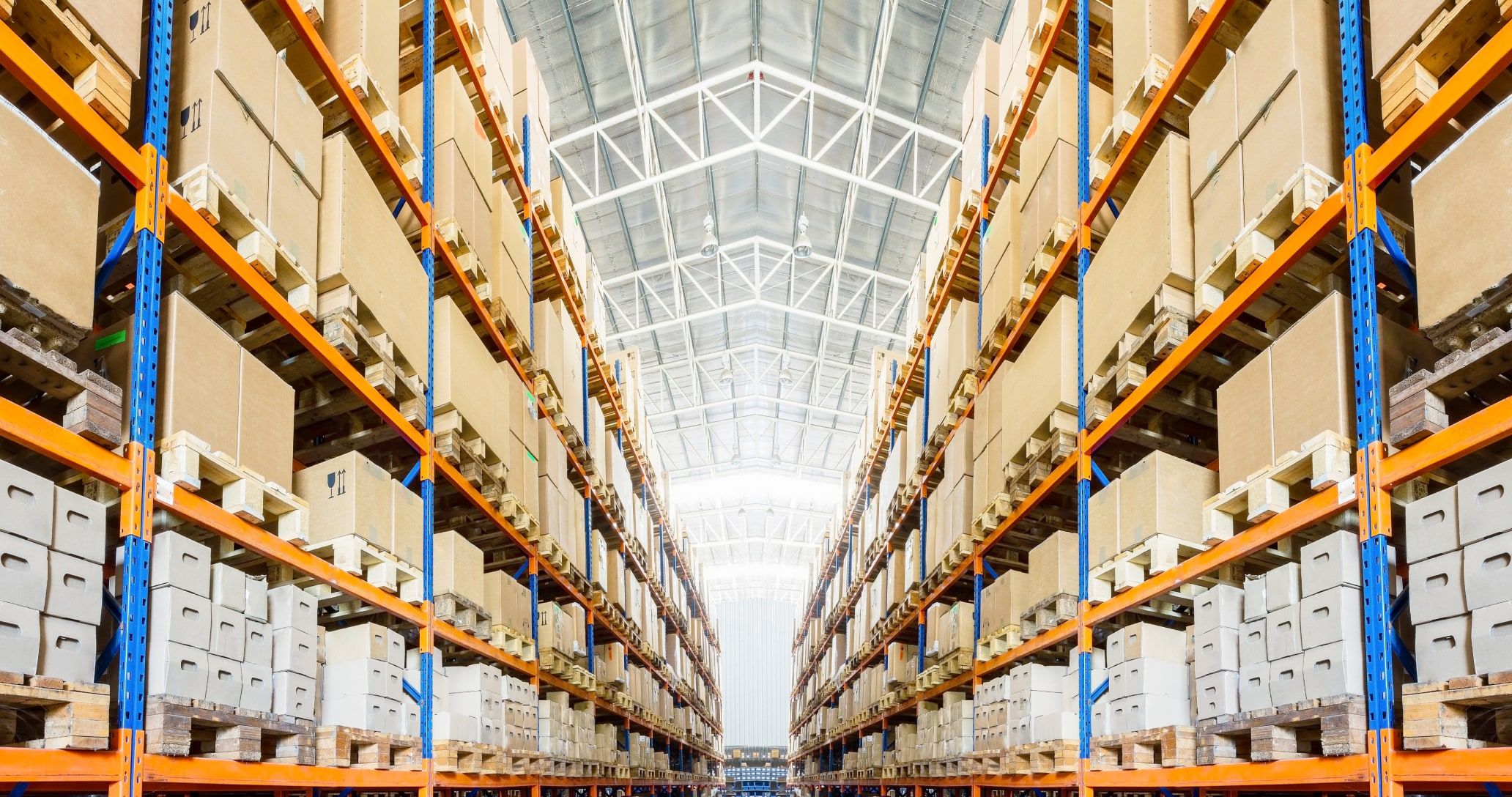 The inside of a giant shipping facility and an wide aisle with many boxes on the shelves